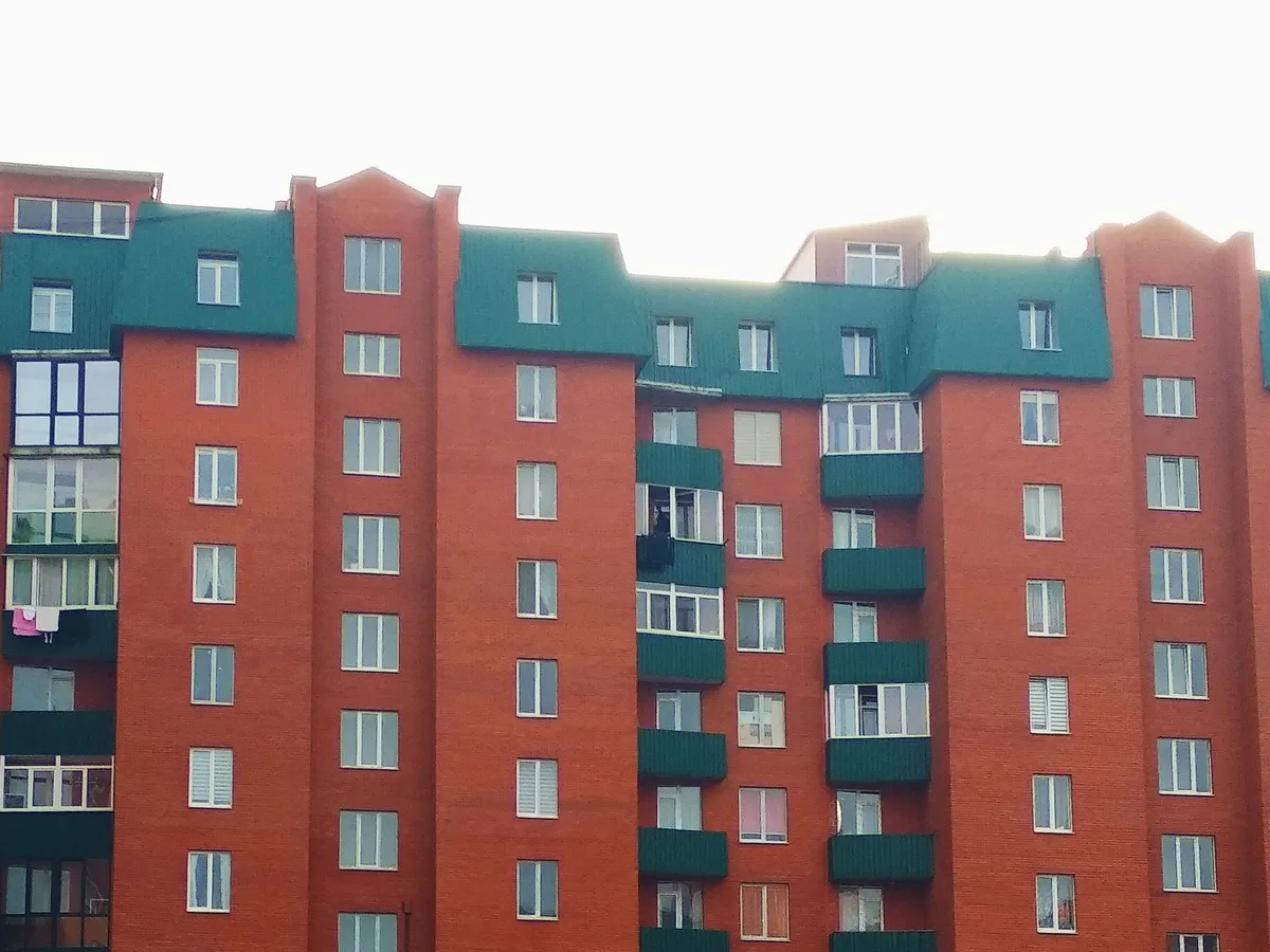Multi-storey red brick apartment building with balconies and many residential windows